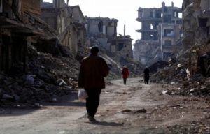 Des personnes marchant entre des bâtiments détruits d'une rue du camp palestinien de Yarmouk