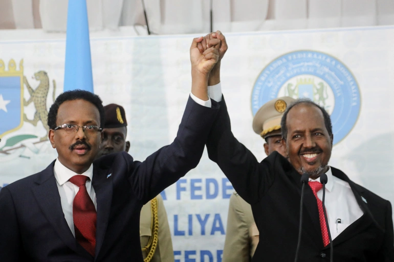 Le président somalien nouvellement élu Hassan Sheikh Mohamud, à droite, tient la main du président sortant Mohamed Abdullahi Mohamed à gauche